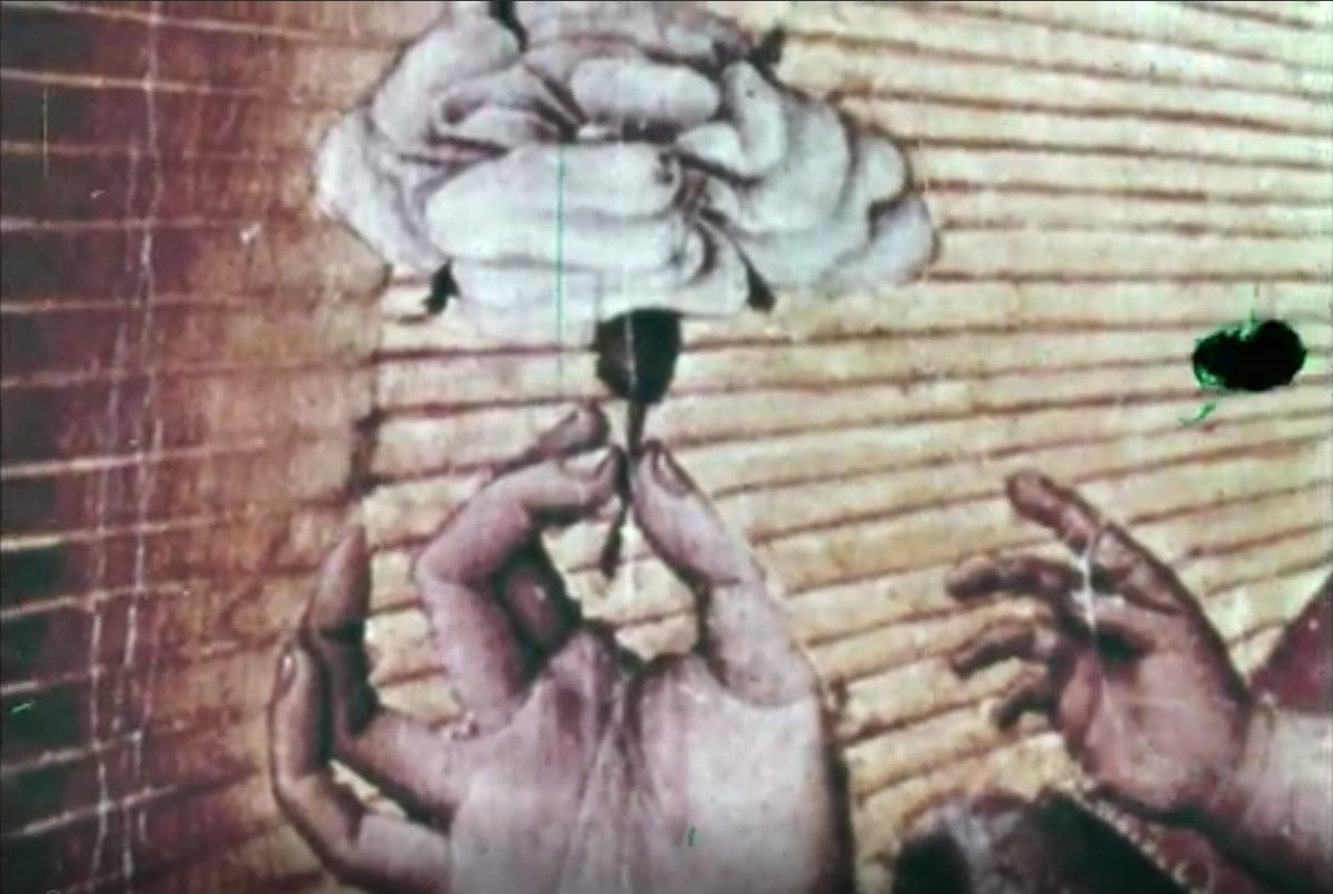Still from Livin’ La Lalaland, hands holding a small object over a textured, warped background